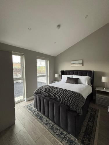 a bedroom with a large bed and a large window at Beyond The Waters Edge Chalet in Dooagh