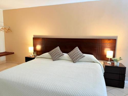 a bedroom with a white bed with two pillows at Regina Hotel in Lunahuaná