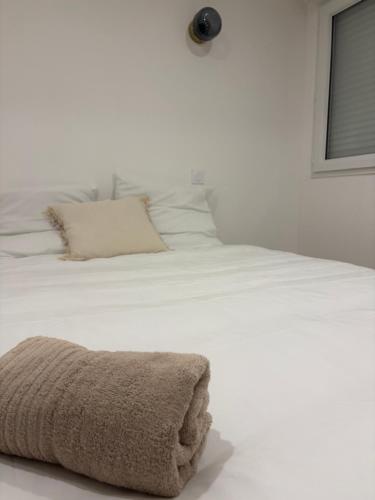 a white bed with a brown towel on it at Charmant appartement moderne D in La Roche-sur-Yon