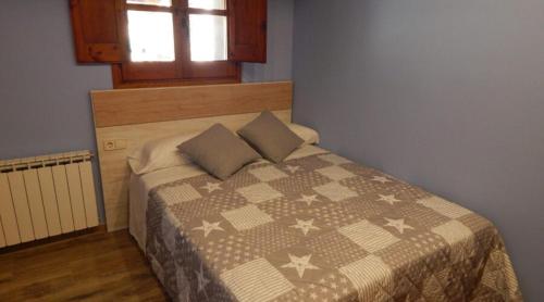 a bedroom with a bed with a comforter and a window at Masia Lledó de Trascastell in Balsareny