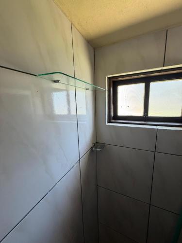 a bathroom with a shower with a window at Casa praia bella torres in Passo De Torres