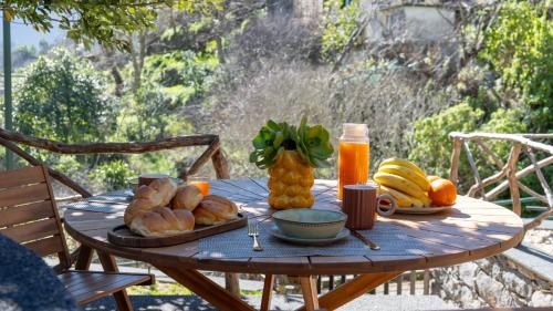 a wooden table with bread and fruit on it at Stonewood Valley by LovelyStay in Curral das Freiras