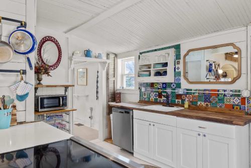 a kitchen with white cabinets and a sink and a mirror at Camp Red Lodge - Cozy & Convenient in Red Lodge