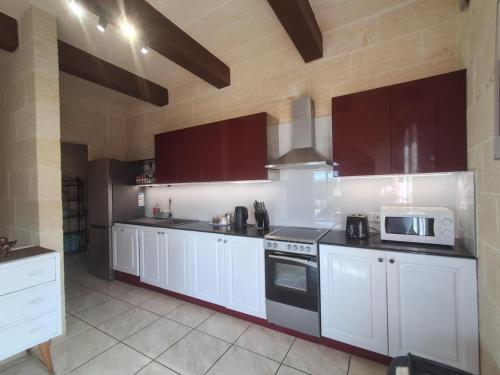 a kitchen with white cabinets and a microwave at Sunsets Farmhouse, Nadur Gozo in Nadur