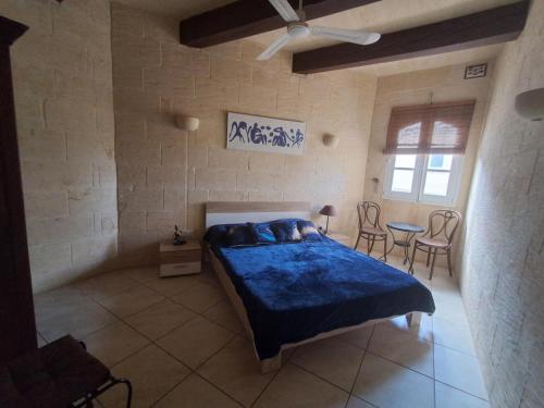 a bedroom with a bed and a table and chairs at Sunsets Farmhouse, Nadur Gozo in Nadur