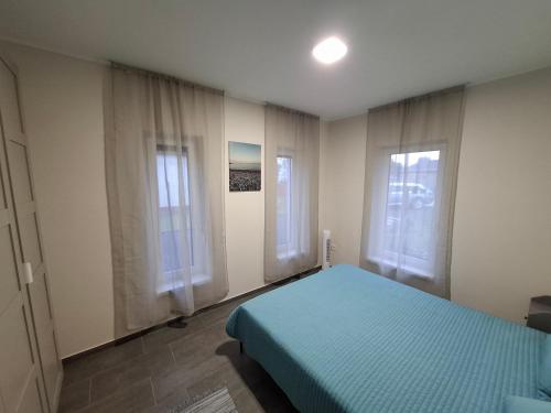 a bedroom with a blue bed and two windows at Offline Home in Balatonőszöd