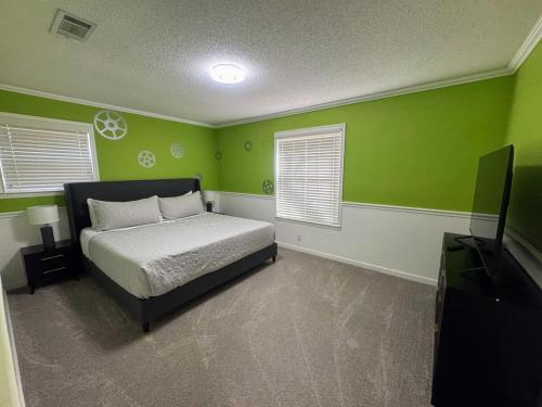 a green bedroom with a bed and a flat screen tv at 4-Bedroom Home with Private Pool in Euless in Euless