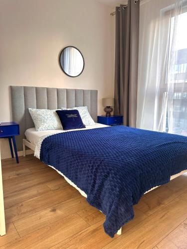 a bedroom with a bed with a blue comforter and a mirror at A63 by Real Apartment in Warsaw