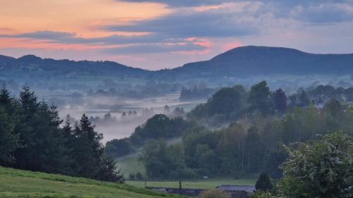 a misty valley with trees and mountains in the background at Oak Hill Escape in Welshpool