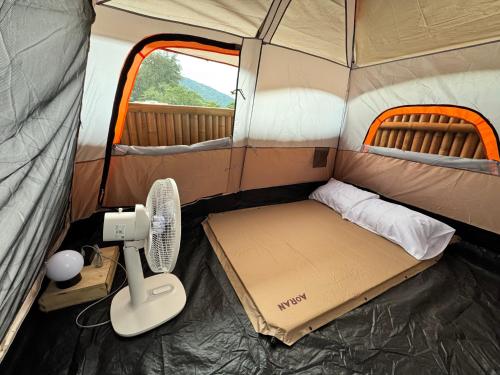 a small tent with a bed and a fan in it at The Tent Naiyang in Nai Yang Beach