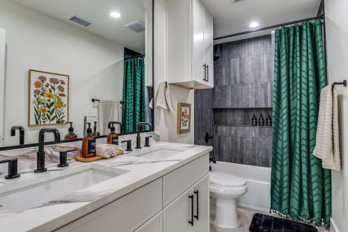 a bathroom with two sinks and a toilet and green shower curtain at La Fleur Chateau 4B 2B Duplex KING Pet Friendly in Richardson