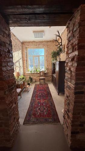 a living room with a brick wall and a rug at Viesnīca Meirānu Muiža in Meirāni