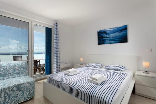 a white bedroom with a bed and a chair at Villa Aster in Privlaka