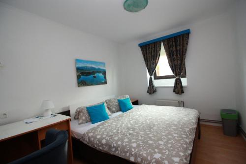um quarto com uma cama, uma secretária e uma janela em Guesthouse Veles em Slovenska Bistrica