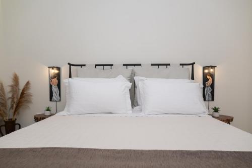a large white bed with white pillows and lamps at Maelia Samos Apartment in Ríva