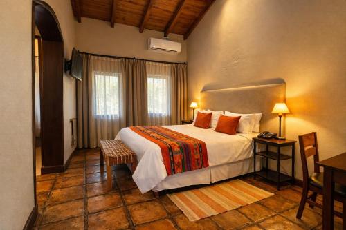 a bedroom with a large bed in a room with a table at Viñas De Cafayate Wine Resort in Cafayate
