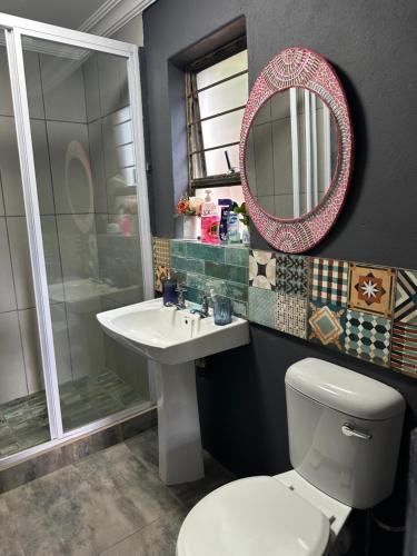 a bathroom with a toilet and a sink and a mirror at Tiny harties in Hartbeespoort