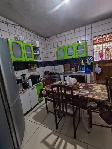 a kitchen with a table and a kitchen with green windows at Quarto para carnaval Olinda e Recife in Paulista