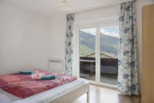 a bedroom with a bed and a large window at Panorama Apartments Semslach in Obervellach