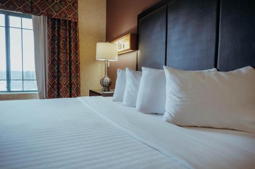 a large bed with white pillows in a hotel room at Wildwood Lodge in Pewaukee