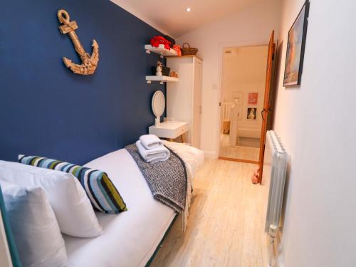 a bedroom with a white bed and a blue wall at The Smokehouse Cottage in Southwold