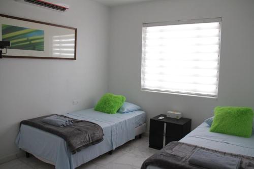 una camera da letto con due letti con cuscini verdi e una finestra di Xevize Apartment 4 a Palm Beach