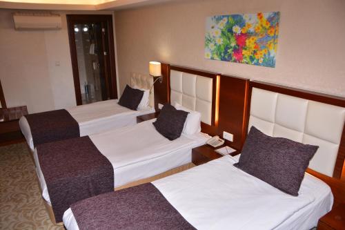 a hotel room with three beds and a painting on the wall at Asrin Business Hotel Kızılay in Ankara