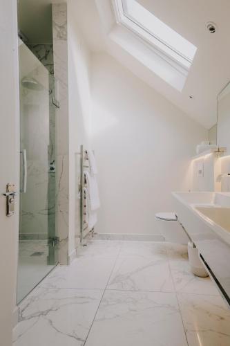 a white bathroom with a shower and a sink at The Galaxie in Oxford