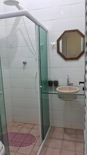 a bathroom with a glass shower and a sink at Pousada Palladium in Neópolis