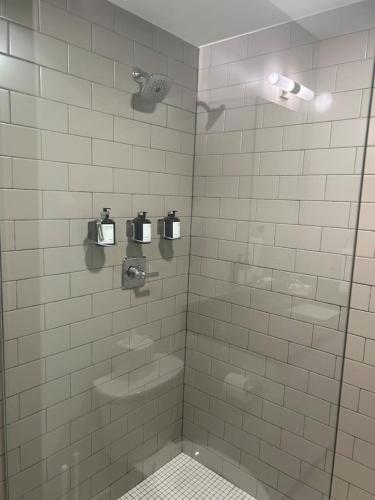 a white tiled bathroom with a shower with a sink at Ther Gregory Suite 101 ADA in New Orleans