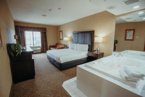 a hotel room with a bed and a bath tub at Wildwood Lodge in Pewaukee