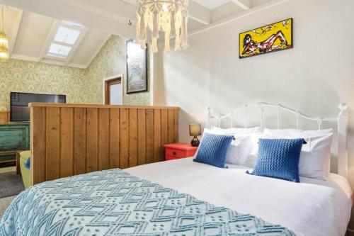 a bedroom with a large bed with blue pillows at Chic Converted Barn in Matakana with Spa in Big Omaha