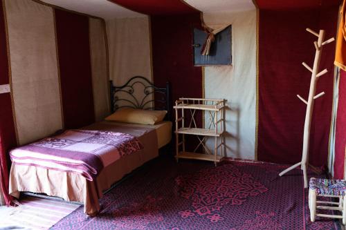 a bedroom with a bed in a room with red walls at Erg Chigaga Regency Camp in El Gouera