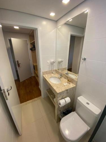 a bathroom with a toilet and a sink and a mirror at Legacy Hotel Guaratinguetá - Ao lado de Aparecida -SP in Guaratinguetá