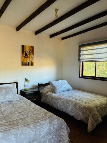a bedroom with two beds and a window at El Descanso Cabins in Capilla Palacio