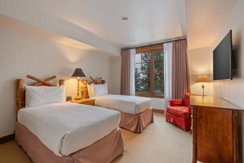 a hotel room with two beds and a red chair at Teton Club in Teton Village