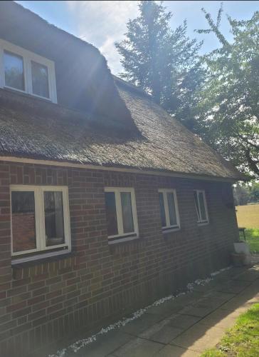 a brick house with a shingled roof at Oakwoods in Holste