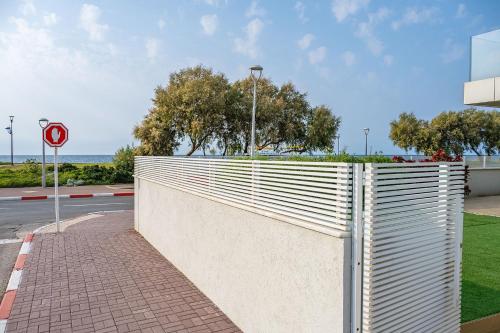 a white fence on a sidewalk next to a street at Myk Beach Nahariya in Nahariyya