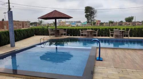 a pool with an umbrella and tables and chairs at Flat Cerejeiras - Condomínio Privado in Bananeiras