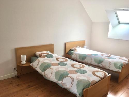 two twin beds in a room with a window at Gîte La Dame du Lac in Paimpont