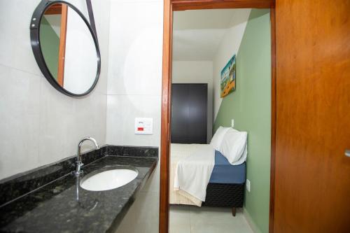 a bathroom with a sink and a bed with a mirror at Jahu Center Casas Un 2 in Jaú