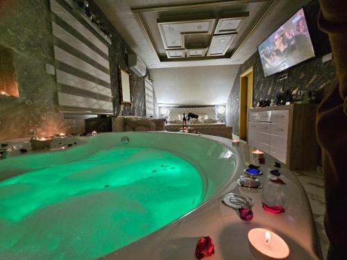 a large tub filled with green water in a bathroom at Jacuzzy Rooms Andjela in Subotica