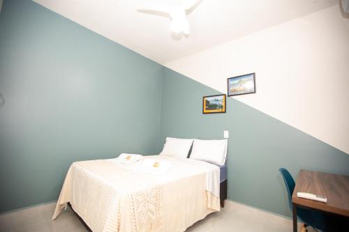 a bed in a room with a blue wall at Jahu Center Casas Un 2 in Jaú