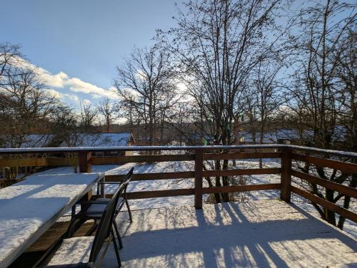 a table and chairs on a deck in the snow at Chalet HEUREux in Somme-Leuze