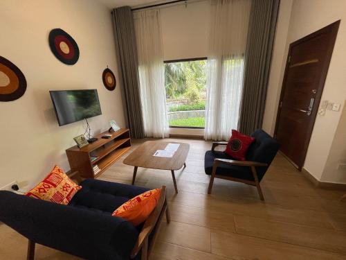 a living room with a couch and chairs and a tv at Lush Garden Chalet in Afiaman