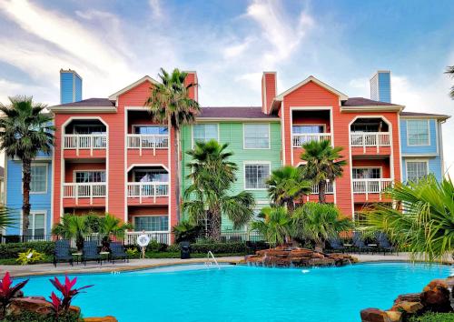 a resort with a swimming pool and palm trees at Dawn 916-Hook, Wine & Sinker in Galveston