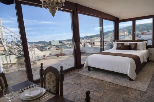 a bedroom with a bed and a table and windows at Royal stylish view apartment in Koropi
