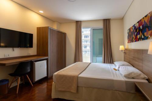 a hotel room with a bed and a desk and a television at Hotel Amalia by Plaza Xavier in São Paulo
