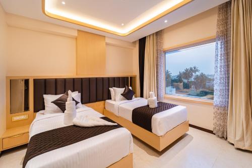 two beds in a hotel room with a window at Ratan International in Pondicherry