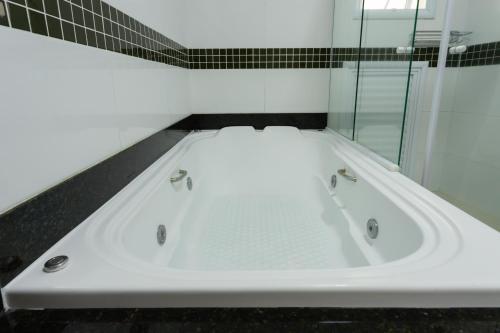 a white bath tub in a bathroom with black tiles at Hotel Amalia by Plaza Xavier in São Paulo